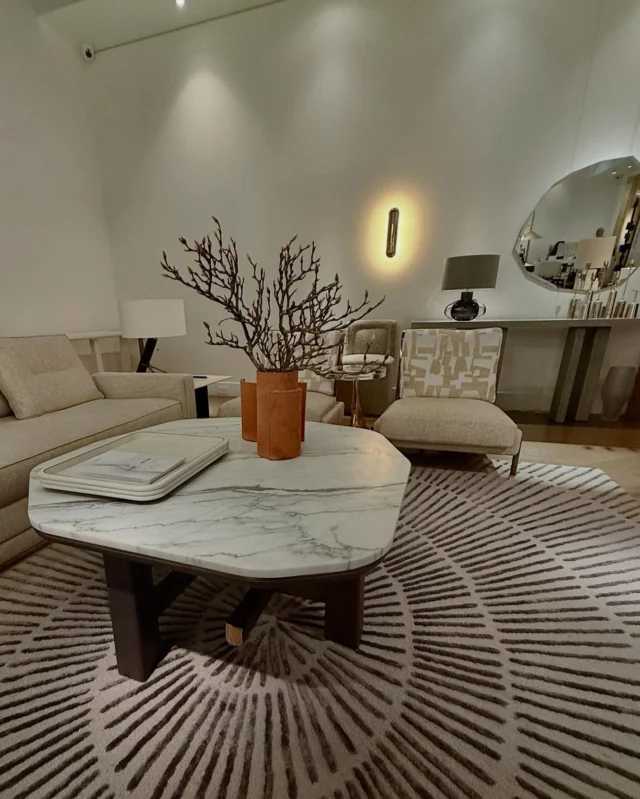 - A refined sitting area centered around a marble-topped coffee table on a circular patterned rug. Soft neutral seating surrounds it, complemented by a terracotta vase with branches. A console with a rounded mirror and a warm wall light adds depth and atmosphere. The overall mood is elegant, calm, and quietly luxurious.•••#SouthHillHome #InteriorDesign #DesignInspiration #LuxuryInteriors
#ShowroomDesign #ModernLiving #MarbleTable #DesignDetails
#NeutralPalette #ContemporaryInteriors #HomeDecorIdeas
#ArtfulLiving #CuratedSpaces